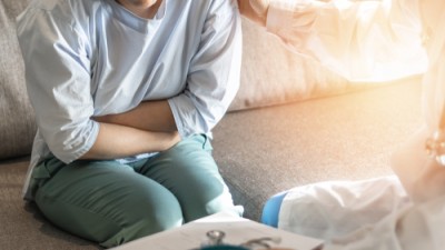 woman sitting on a doctors couch holding stomach